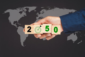 Hand holding of wooden cubes with letters 2050 against the world map background