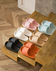 Set of house slippers for whole family. Six pairs of colorful slippers in row on steps of wooden staircase. Rubber Shoes. Shower slippers. Men's and women's slippers. Top view. Soft focus. Copy space