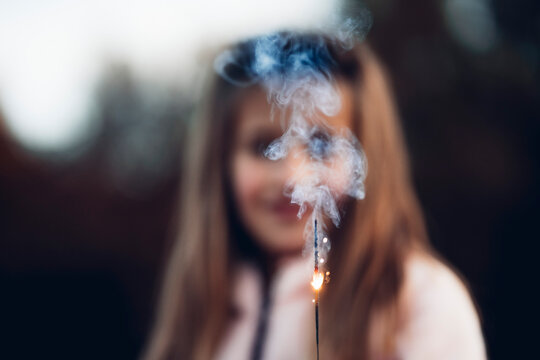 A beautiful girl has fun with the sparks of a flare.