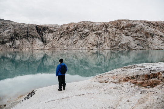 A man looking at the rough landscape by 'Twin Glacier' in Greenland
