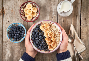 Hands holding a bowl with homemade oatmeal granola with  blueberry and