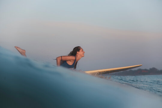 Side view of woman lying on surfboard