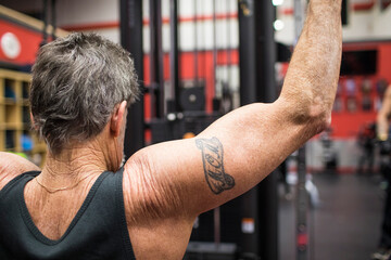 Elderly man doing Lat Pull Down exercise on gym equipment