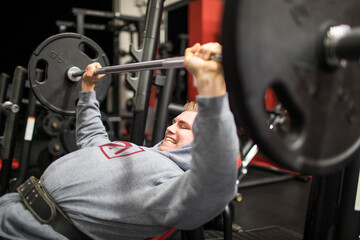 Fit millennial training muscles with incline bench press in gym