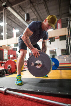 Male athlete placing weights on barbell at the gym