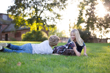 kids siblings playing together in grassy field outside