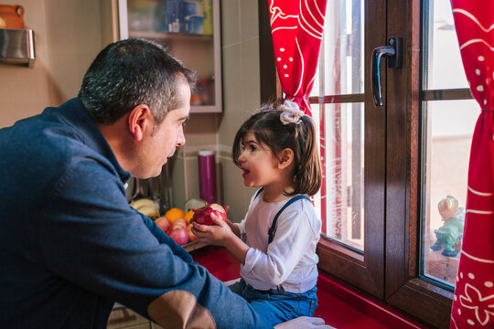 Father talking to little girl while eating a piece of fruit in the kit