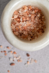 Fototapeta na wymiar Close-up pink himalayan salt in a mortar for seasoning on a marble background, top view, close-up