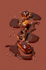 Art with an eclair. Broken eclair in puddles of icing on brown background. Conceptual monochrome...