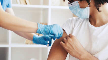 Vaccine shot. Virus immunization. Influenza prevention. Unrecognizable doctor hands in gloves giving injection jab dose to male patient arm shoulder. - obrazy, fototapety, plakaty