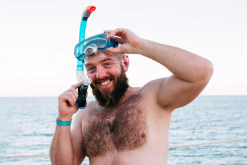 Bearded man in diving mask on a tropical island. Male tourist having fun diving on sea background....