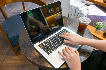 Close up of Woman working with laptop at table indoors working space, work from home coffee shop.