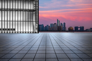 Fototapeta na wymiar Empty square floor and glass wall with city skyline at sunrise in Hangzhou, China.