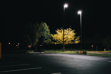 Empty parking lot lit by street lights. - obrazy, fototapety, plakaty