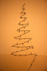 Ausgeschaltete alte Lichterkette in Form eines Weihnachtsbaums hängt trostlos an einer Wand mit...