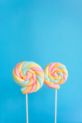 Rainbow twist roll marshmallow like lollipop on blue background 