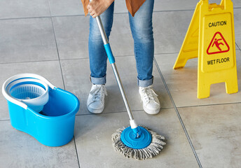 Floor mopping, cleaning sign and mop bucket with water and woman doing safety and hygiene work....