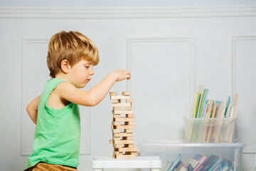 Close-up of boy build a tower playing with Jenga wooden blocks