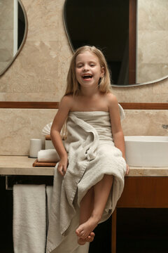 Portrait of cute little girl wrapped in towel in the bathroom