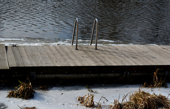 frozen river has modified entrances to water from  embankment. swimmer decides to take a bath as part of conditioning and hardening after sauna, it is possible to use stainless steel steps, ladder