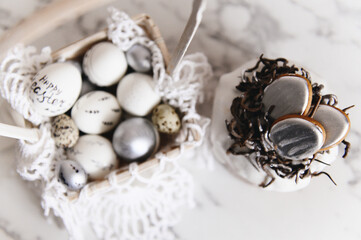 Painted silver and white Easter eggs on a light background and cake, postcard, free space for text, selective focus
