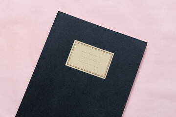 notebook nero chiuso su sfondo rosa chiaro foto orizzontale