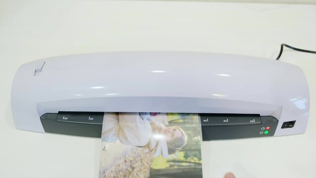 A machine for laminating photos and documents with plastic. Desktop white laminator, close-up