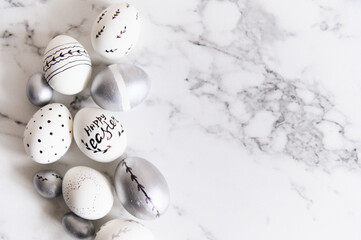 Painted silver and white Easter eggs on a marble background, postcard, free space for text