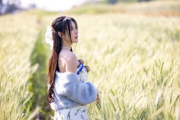 Fototapeta na wymiar Beautiful woman outdoors enjoying nature and grain barley field in sunlight. Young woman standing and touch grain barley. Beautiful woman walking and running in barley field. Freedom concept.
