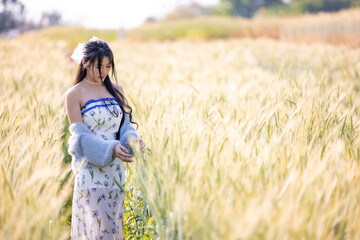 Fototapeta na wymiar Beautiful woman outdoors enjoying nature and grain barley field in sunlight. Young woman standing and touch grain barley. Beautiful woman walking and running in barley field. Freedom concept.