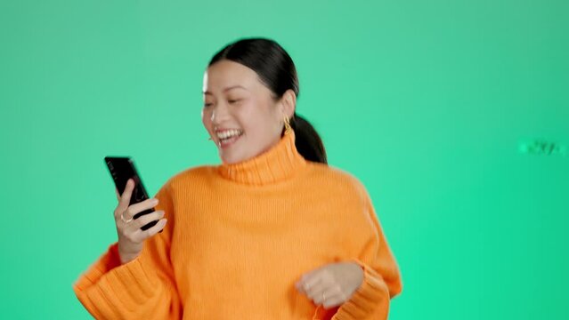 Asian winning money on a phone isolated on studio background online competition, prize or giveaway bonus. Winner, wow and excited person in China with cash, lotto or lottery on mobile app dancing