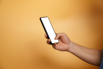 Fototapeta na wymiar Close up of male hands using smartphone isolated on orange wall. Male hand showing blank white screen of modern smartphone. Businessman holding a mobile phone and unlocking it with his fingerprint