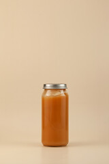 Fruit puree in tall glass jar with metal lid. Baby food, the first complementary food. Design element, copy space