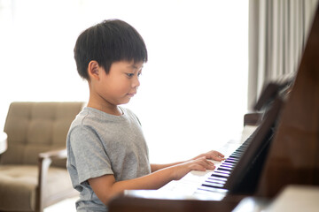 Asian young musician boy kid having fun activities play piano music lesson in music education at...