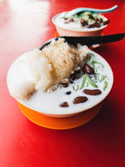 Malaysia traditional iced sweet dessert Cendol served in a bowl with coconut milk and red beans.