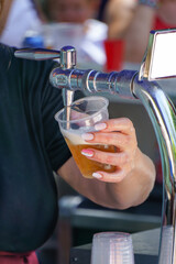 woman with painted fingernails serving a draught beer with foam