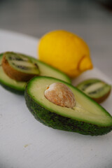 Cut in half avocado and kiwi, lemon isolated green on a table. Healthy eating food fruit organic fresh