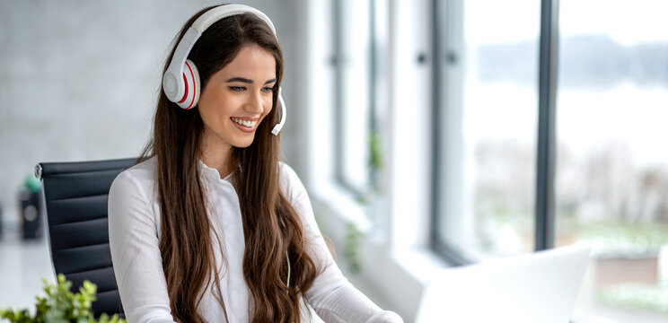 Portrait of costumer support consultant talking on hands-free phone at office.