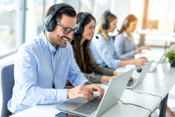 Happy male customer service assistant with headset chatting with client during online phone call...