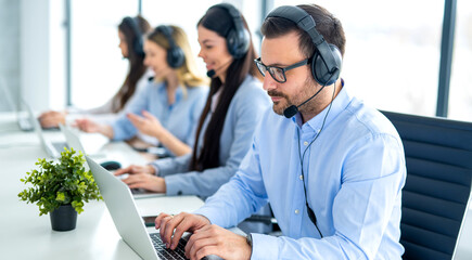 Call center operator agents in headset communicating with clients at online support service office....