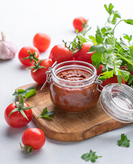 Salsa sauce is a traditional Mexican sauce with tomatoes and hot peppers on a light background with fresh herbs close up.