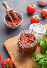 Homemade tomato sauce for pizza or pasta in a jar on a gray background with fresh vegetables, herbs and spicy.