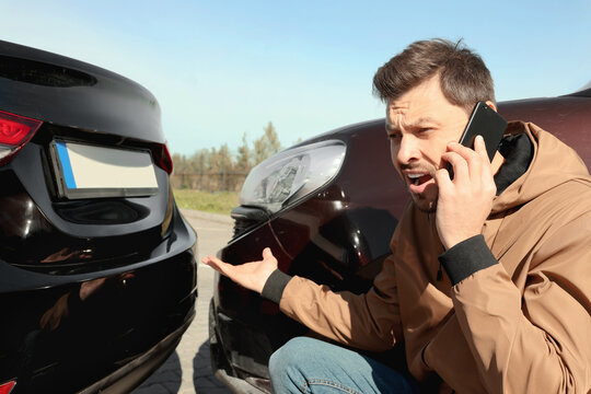 Man talking on phone near car with scratch outdoors Auto accident