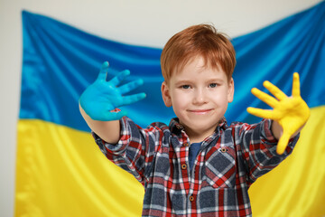 Little boy with painted hands near Ukrainian flag. Love Ukraine concept