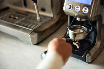 A woman holding a coffee holder and making a fresh morning coffee at home.