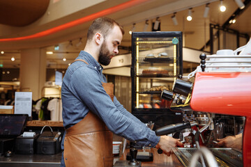 A man and a girl make coffee at a coffee machine in a coffee shop