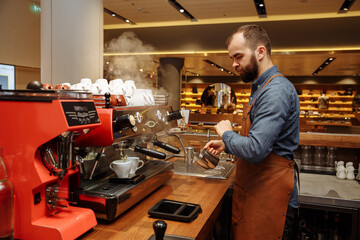 A man and a girl make coffee at a coffee machine in a coffee shop