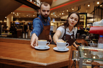 A man and a girl make coffee at a coffee machine in a coffee shop