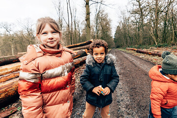 Young children are outdoors wearing windbreakers along a dirt road in the woods © Carlo Prearo