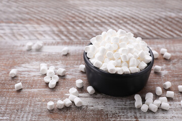 Fototapeta na wymiar Bowl with delicious marshmallows on wooden table